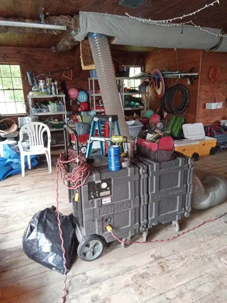 Portable HEPA vacuum machines connected to overhead ductwork during an air duct cleaning.