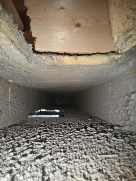Debris and dust inside an insulation-lined air duct before Armstrong's cleaning.