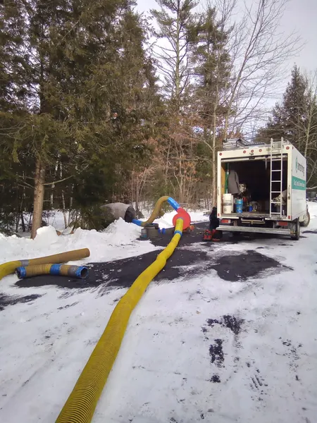 Armstrong's truck-mounted vacuum hoses running across a snowy driveway during a winter air duct cleaning.