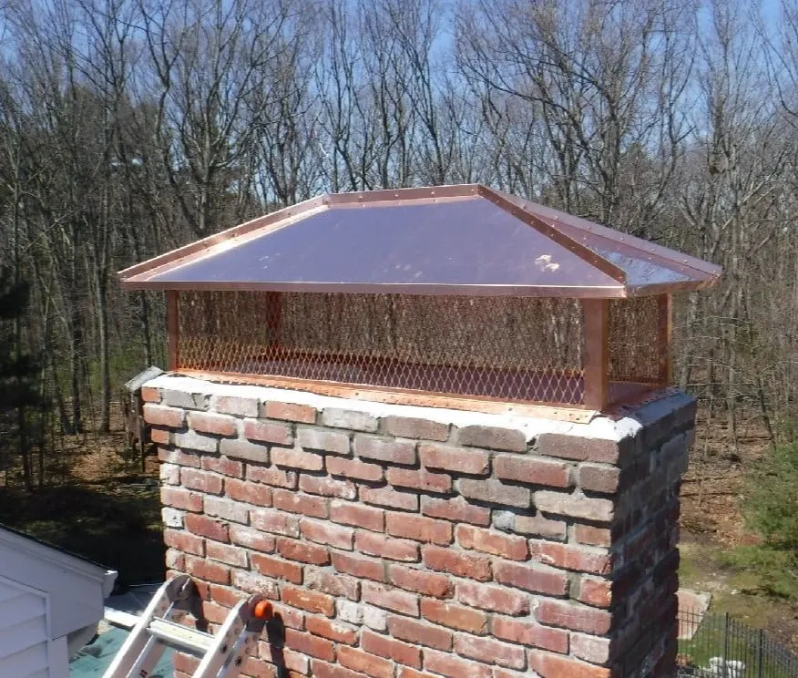 Custom copper chimney cap with a hip-style roof and copper mesh covering the full brick chimney crown.