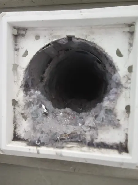 Lint accumulating inside a round dryer vent duct, seen with the exterior cover removed.
