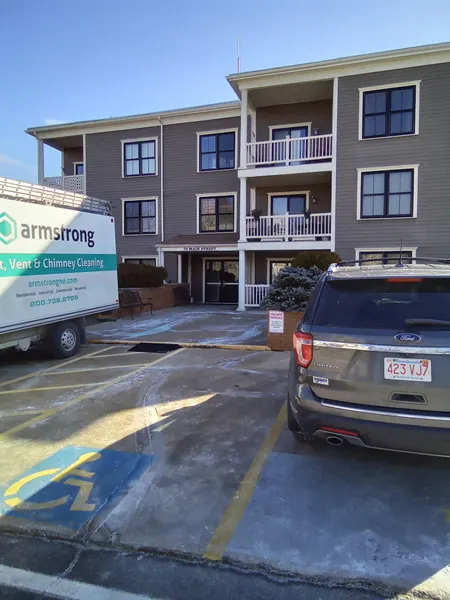Armstrong service truck parked at a three-story apartment building for dryer vent cleaning.