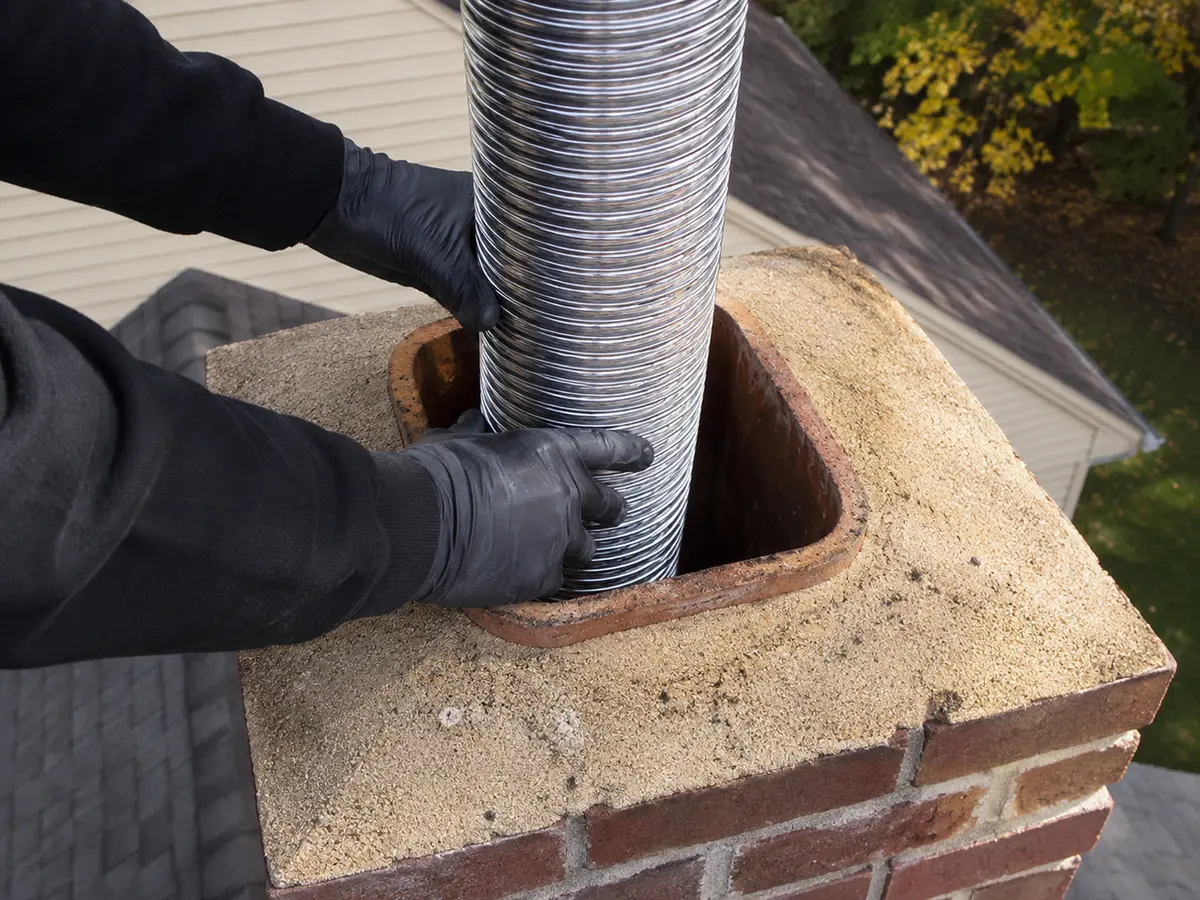 Stainless steel chimney liner being installed in a masonry chimney