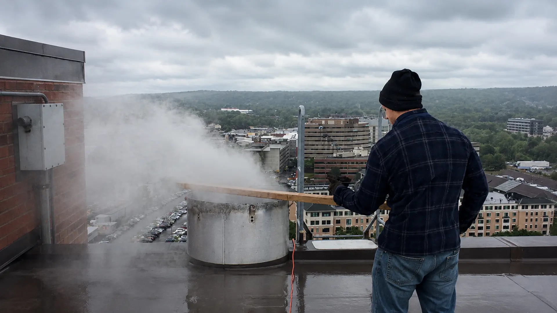 Technician high-pressure washing the interior of a high-rise trash chute